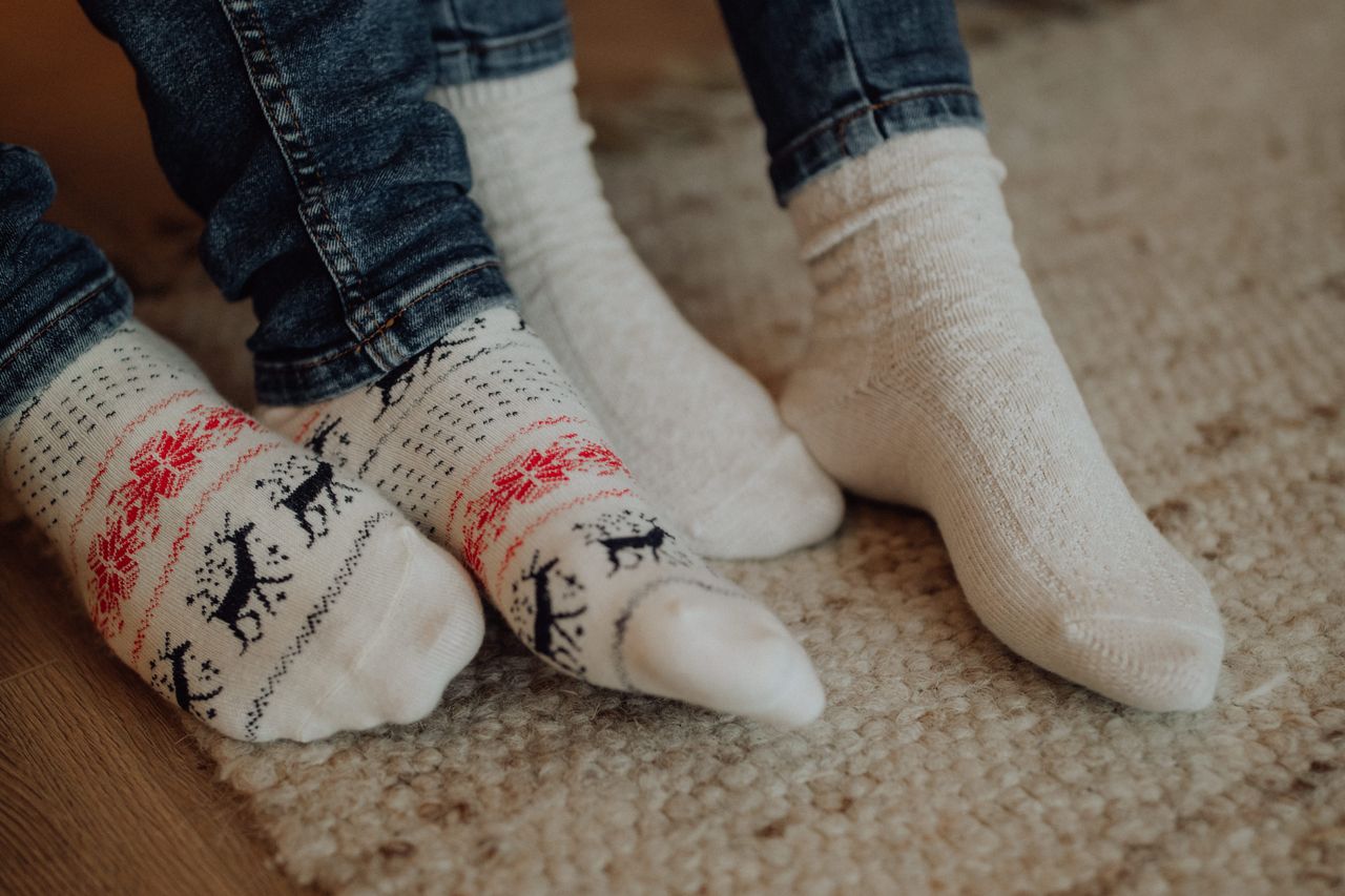 Mastering the First Impression: Your intriguing post title goes here Two people wearing festive socks on a cozy carpet floor indoors.