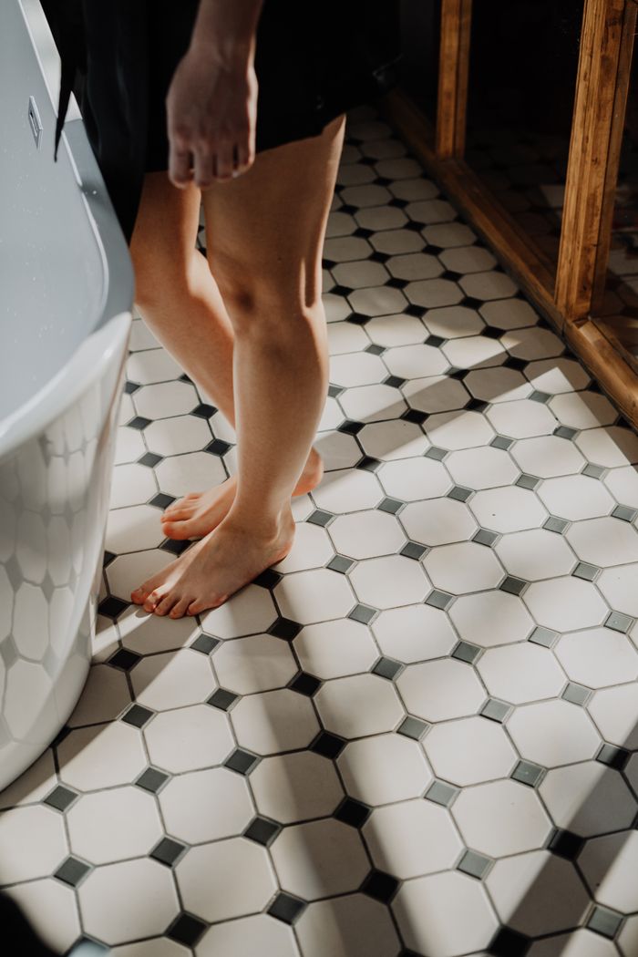 Crafting Captivating Headlines: Your awesome post title goes here A young woman stands barefoot on sunlit tiled bathroom floor, emphasizing relaxation.